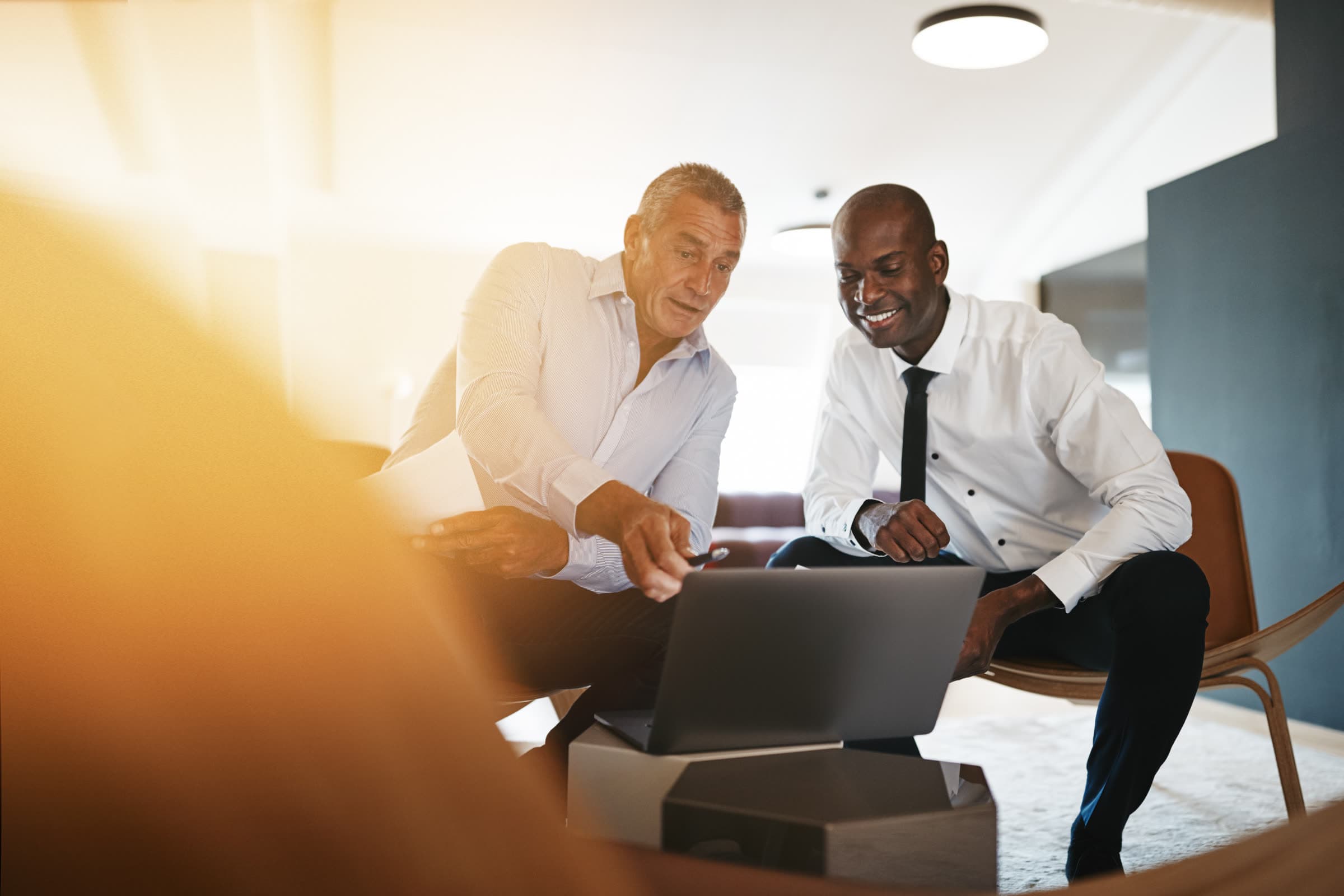 Two business partners reviewing figures on a laptop in an office lounge