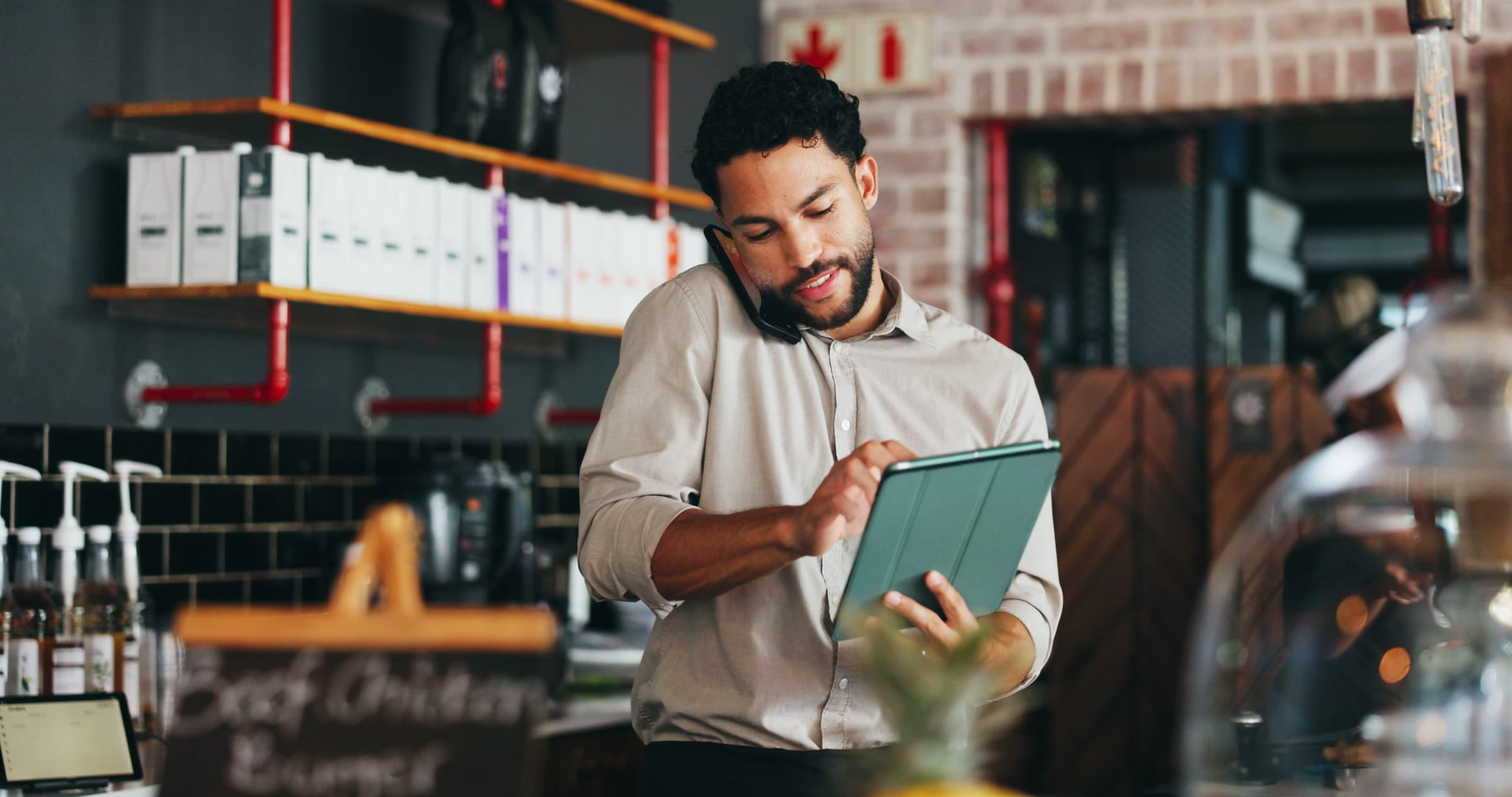 A business owner on the phone using a tablet in their shop