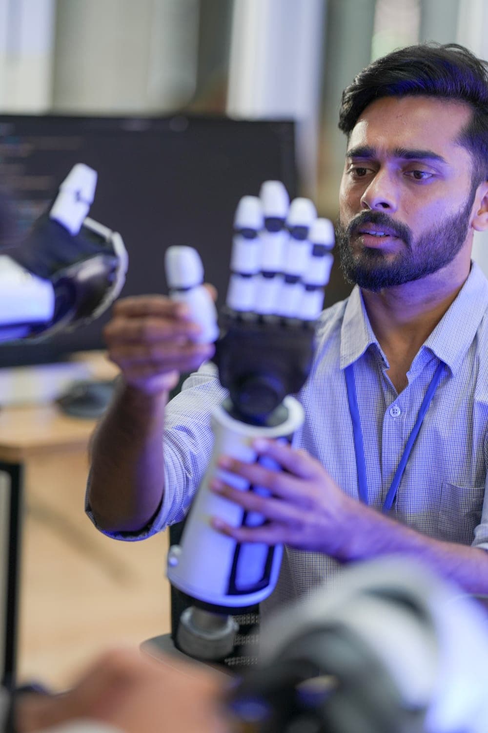 An engineer examining a robotic hand prototype in a research lab