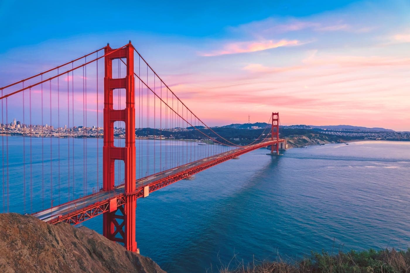 The Golden Gate Bridge at sunset, the San Francisco skyline across the bay